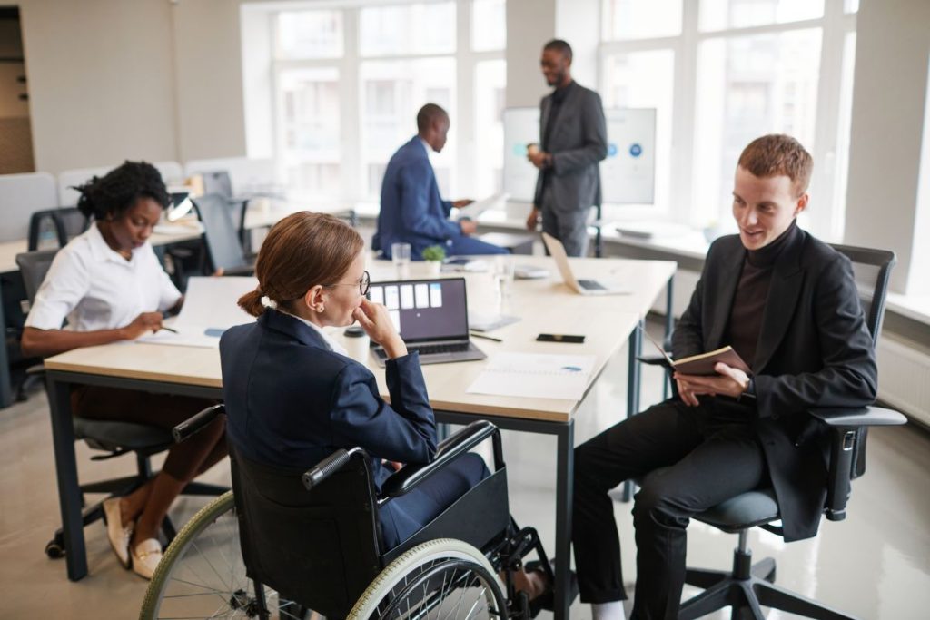 Portrait of successful businesswoman using wheelchair while speaking to male colleague in meeting, copy space