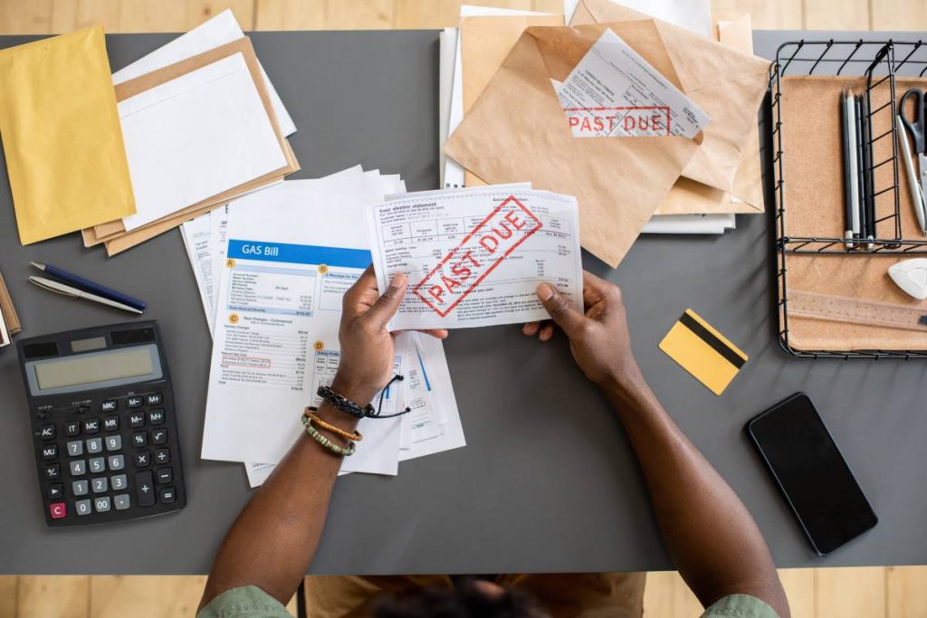 High angle view of unrecognizable blackman sitting at table with bills and checking arrears of payment