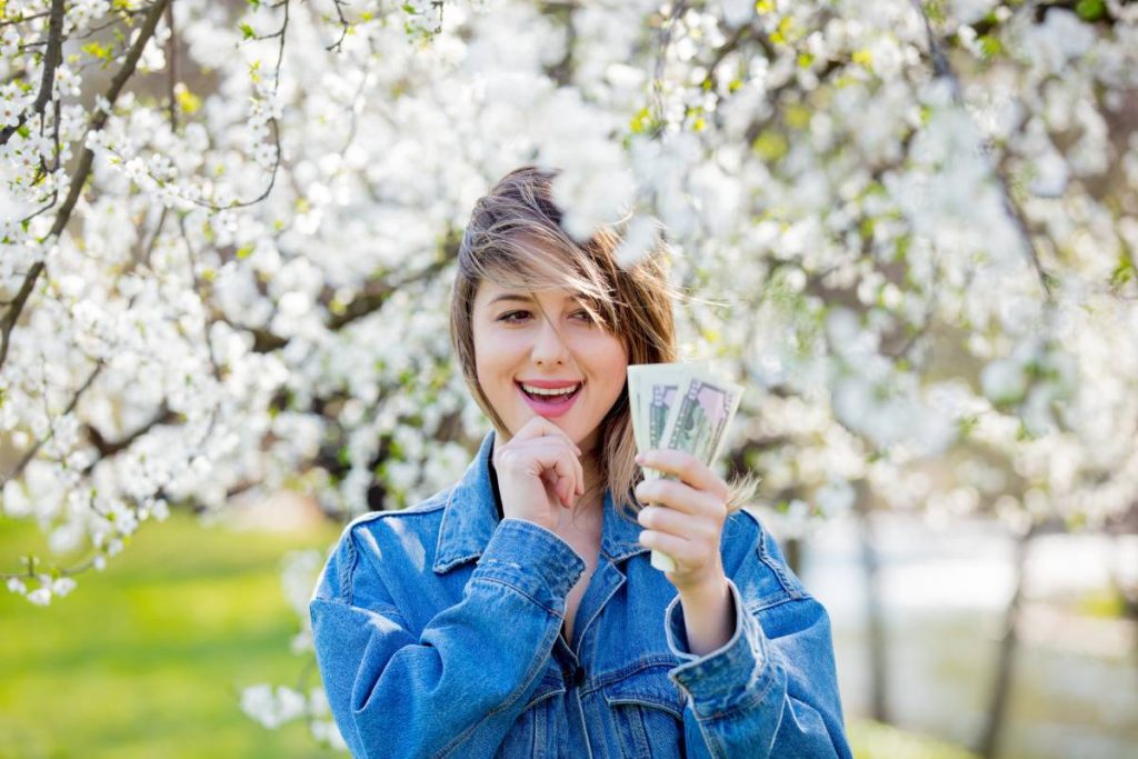 girl in a denim jacket and money stands near a flowering tree in the park. Spring season