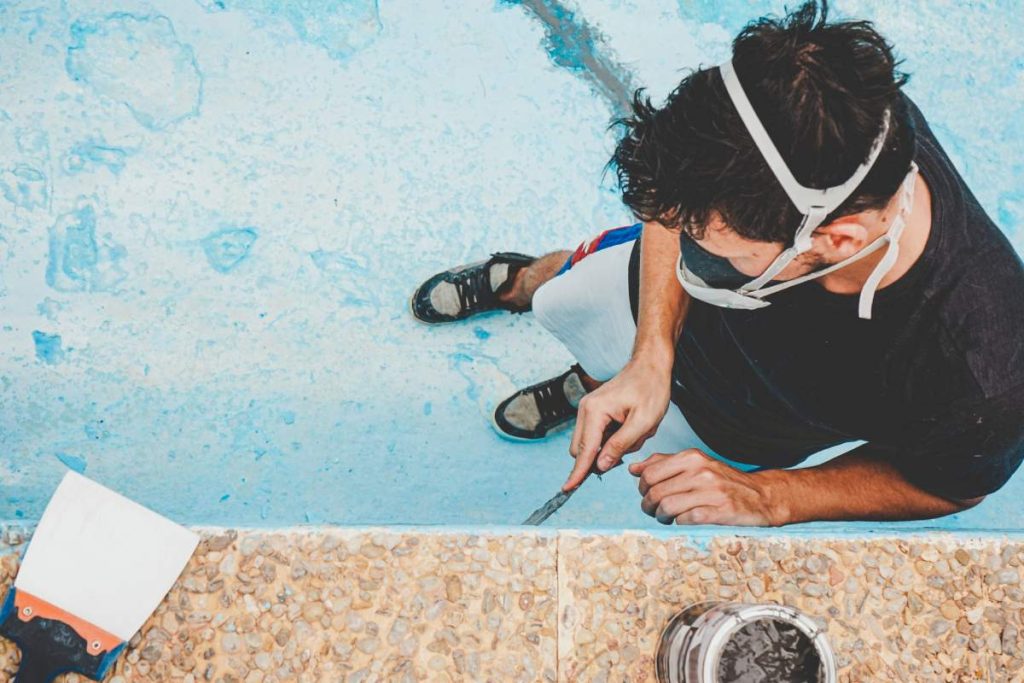 Young man working pool resurfacing