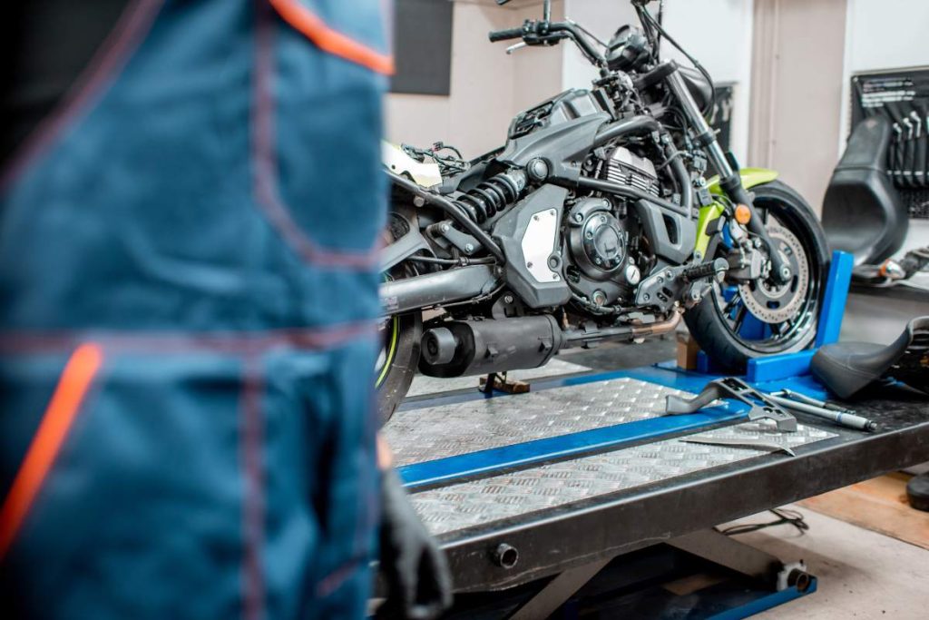 Sports motorcycle during a maintenance with repairman on the foreground at the workshop