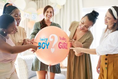 Shot of a group of women about to pop a balloon for a gender reveal during a baby shower.