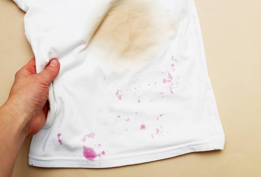 dirty stains on a white T-shirt from berries and drink on brown background.