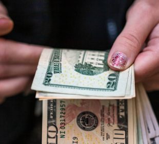 A closeup of female hands counting USD banknotes - world money, inflation and economy concept