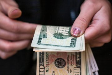 A closeup of female hands counting USD banknotes - world money, inflation and economy concept
