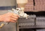 A shallow focus shot of human hands holding a paint sprayer in the workshop