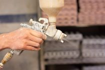 A shallow focus shot of human hands holding a paint sprayer in the workshop