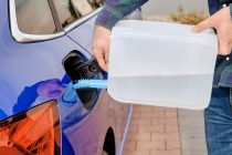 Close up man filling a diesel engine fluid from canister into the tank of blue car. Diesel exhaust fluid for reduction of air pollution. Environmental friendly and eco solution