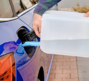 Close up man filling a diesel engine fluid from canister into the tank of blue car. Diesel exhaust fluid for reduction of air pollution. Environmental friendly and eco solution